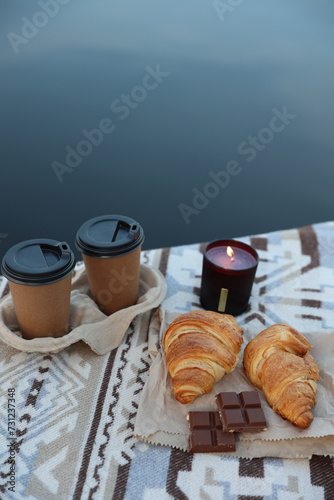 romantic vacation near the lake. Picnic on a wooden pier by the lake with food, croissants, coffee, chocolate and candles. aesthetic photo near the lake. autumn vibe