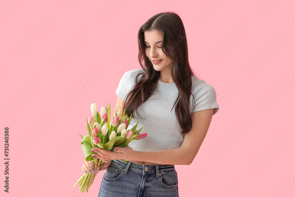 Pretty young woman with bouquet of beautiful tulips on pink background. International Women's Day