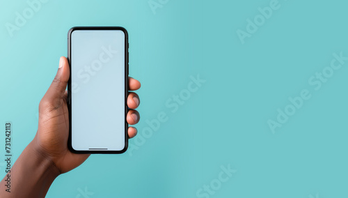 A human hand holding a smartphone, cell phone, mobile phone on a blue, green background. Mock-up concept. Copy space for text, advertising, message, logo photo
