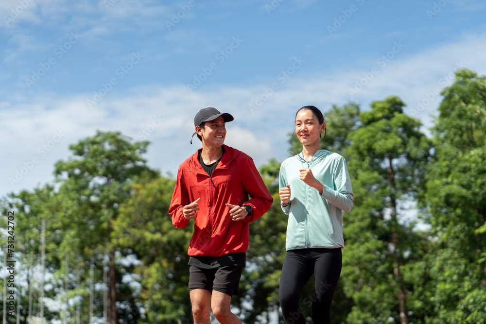Asian Couple jogging and running outdoors at sport stadium. Happy Man woman wearing sportswear jogging. Male and female in running uniform at outdoor. Workout exercise. Healthy and lifestyle. Asian Couple jogging and running outdoors at sport stadium. Happy Man woman wearing sportswear jogging. Male and female in running uniform at outdoor. Workout exercise. Healthy and lifestyle.