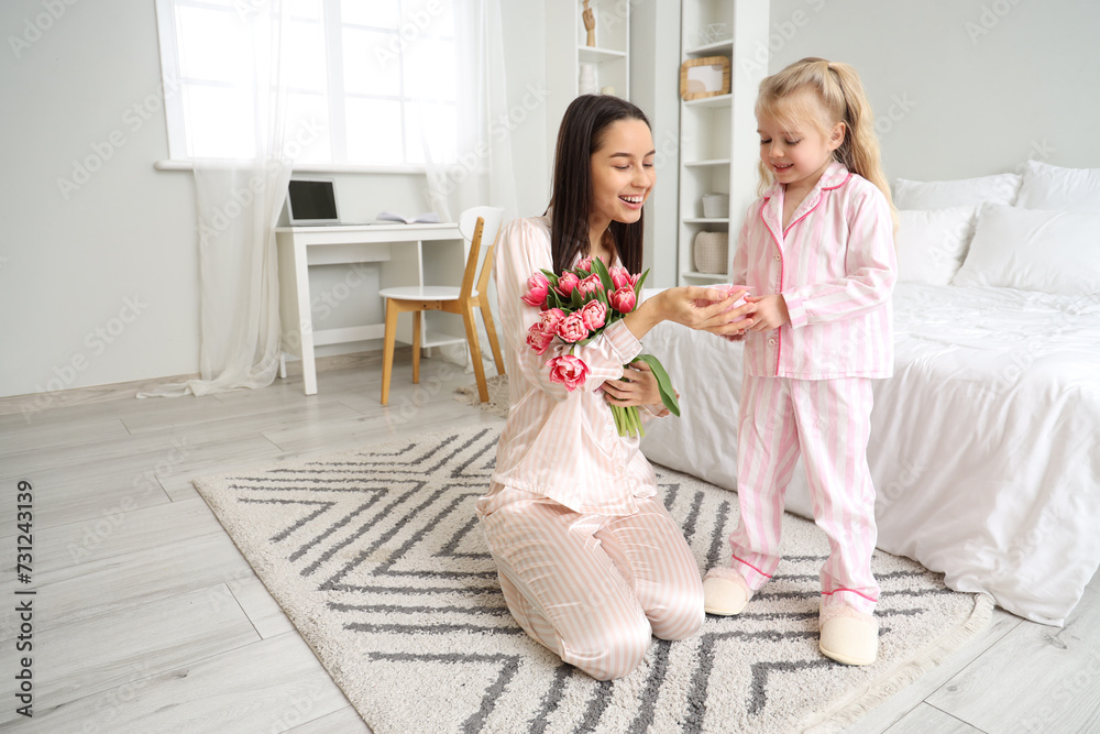 Φωτογραφία Little girl congratulating her happy mom with bouquet of beautiful flowers and gift box in bedroom