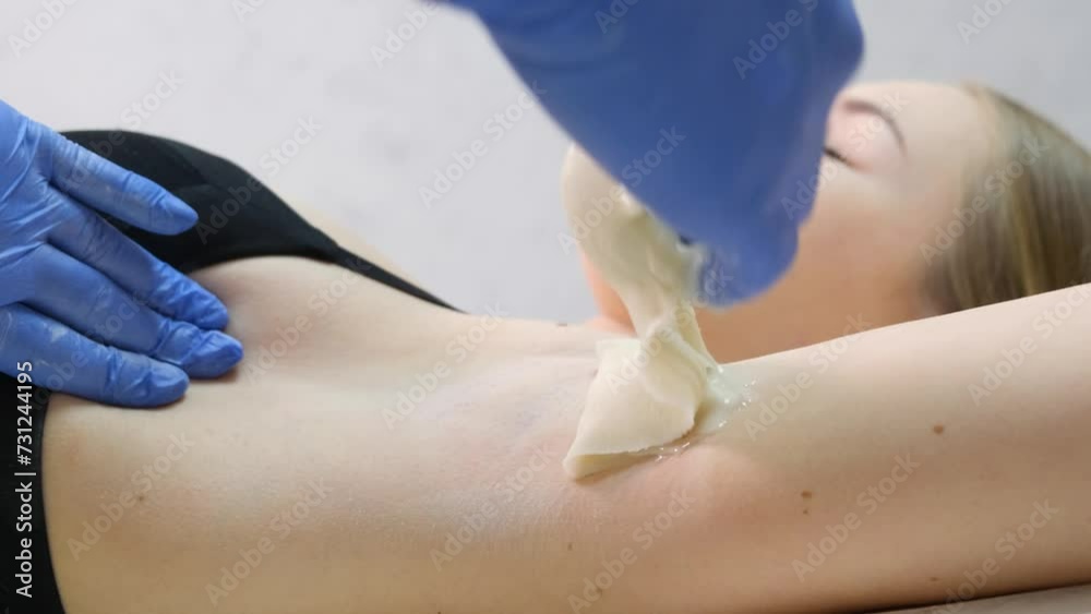 Hand of cosmetologist applying wah paste on armpit. Smooth underarm concept.