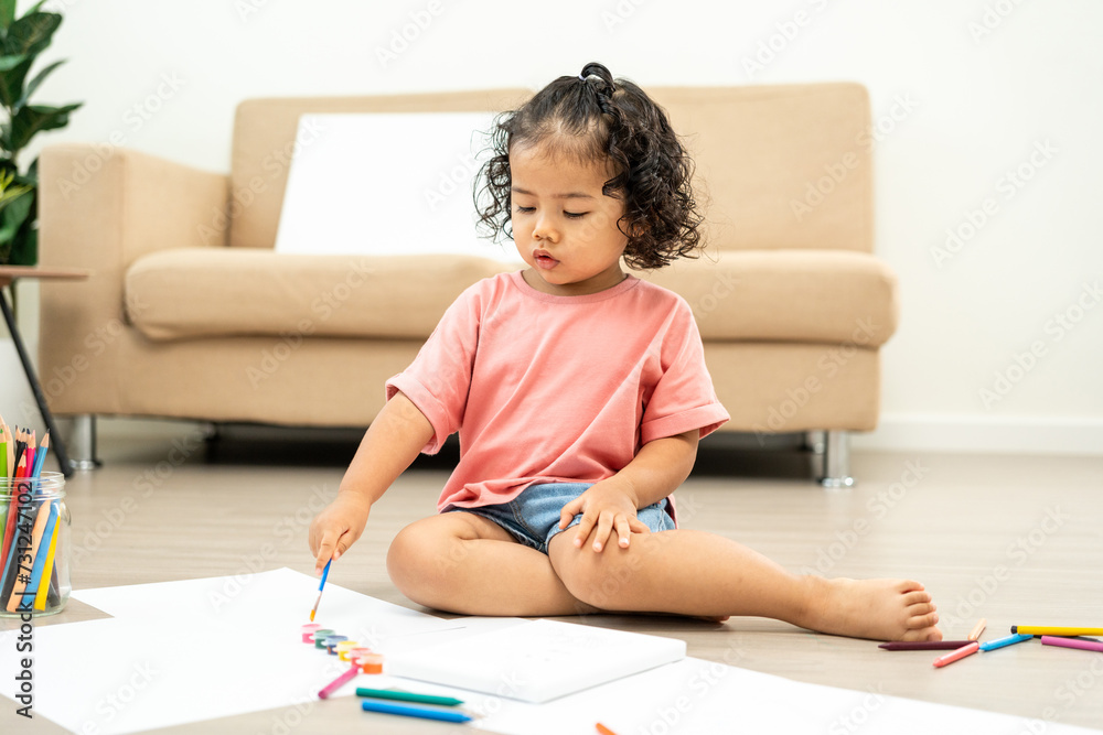 Happy moment little cute girl creating and water color painting activity with paint brushes on frame canvas at living room. Kids activity. Child physical, Emotional, Cognitive development concept. Happy moment little cute girl creating and water color painting activity with paint brushes on frame canvas at living room. Kids activity. Child physical, Emotional, Cognitive development concept.