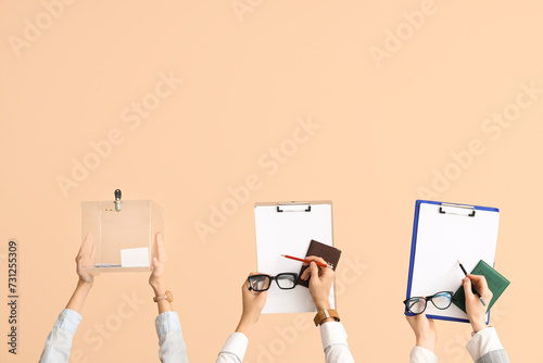 Hands holding ballot box, passports and clipboards with voting papers on beige background. Election concept