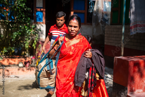 South asian hindu religious married rural couple leaving their home for a holiday trip , People in traditional red costumes 