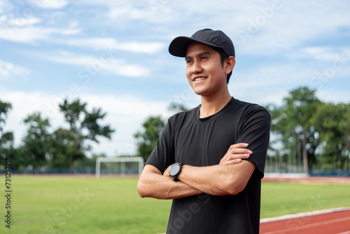 Young handsome asian man wearing sportswear standing post on running track at sport stadium outdoor. Portraits of Indian man jogging on the road. Training athlete outdoor concept.