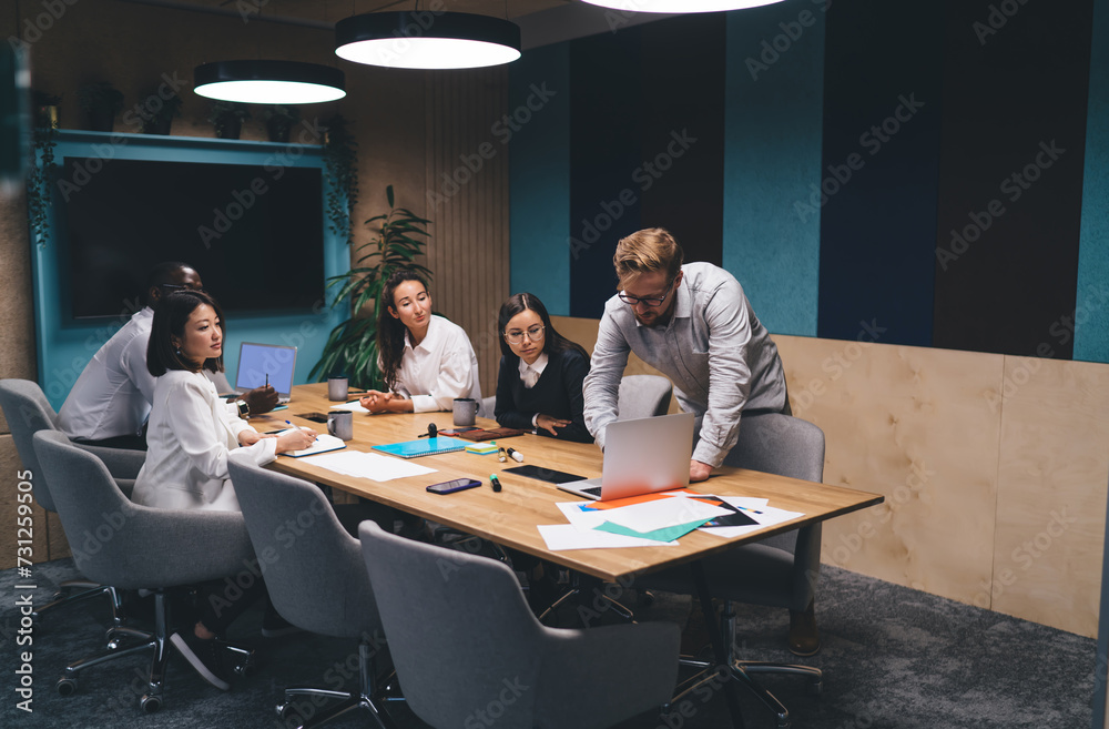 Male leader showing presentation on laptop to multiethnic colleagues Male leader showing presentation on laptop to multiethnic colleagues