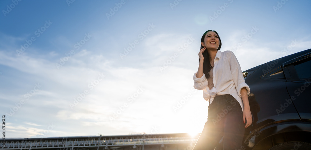 Young beautiful asian women buying new car. she was standing near car on the roadside. Beautiful moment blue sky Smiling female driving travel by vehicle on the road on a bright day with sun light. - obrazy, fototapety, plakaty 