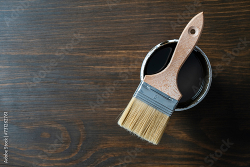 Top view on paint brush on the opened can on wooden table background or floor painting and renovation repairing concept, copy space