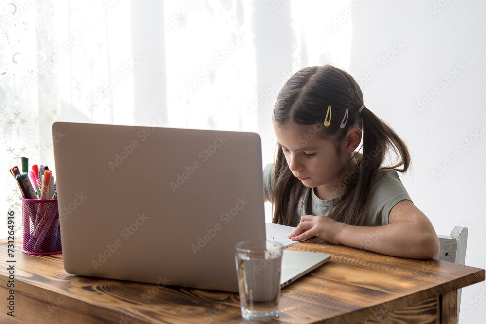 Distance education, schoolgirl studying online on laptop at home, sitting at table and communicating with teacher. Distance education, schoolgirl studying online on laptop at home, sitting at table and communicating with teacher.