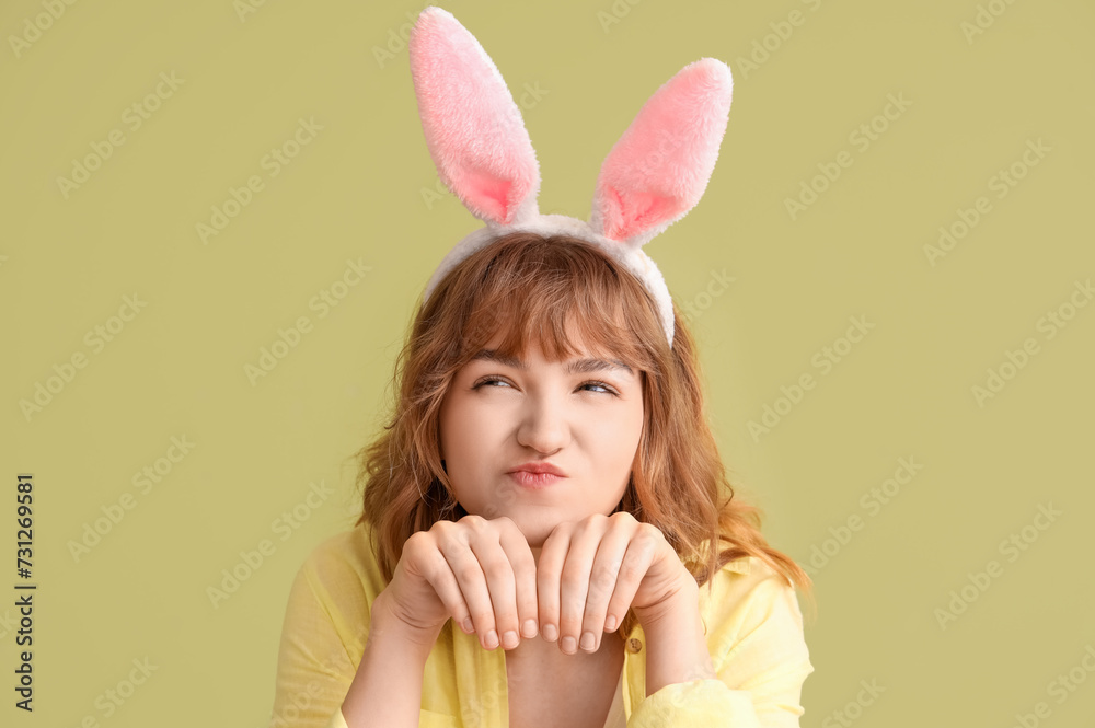 Funny young girl with Easter bunny ears on color background