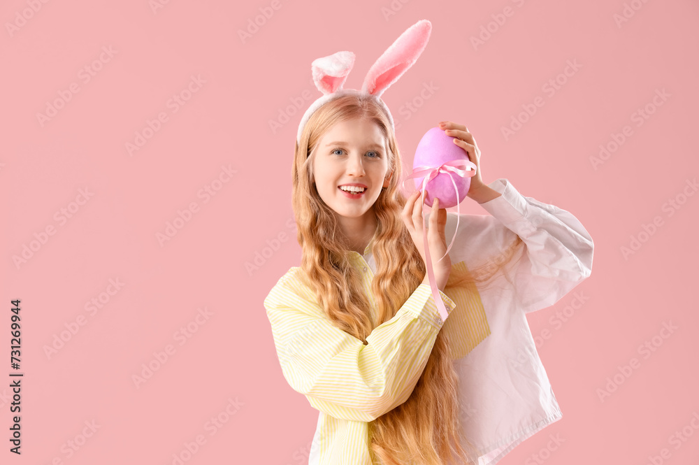 Young girl with bunny ears and Easter egg on pink background