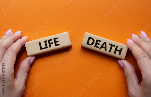 Life or Death symbol. Concept word Life or Death on wooden blocks. Businessman hand. Beautiful orange background. Business and Life or Death concept. Copy space
