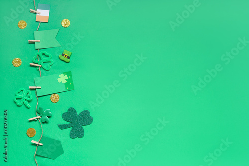 Paper garland with clover and Irish flag for St. Patrick's Day celebration on green background