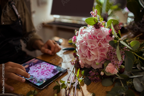 Florist taking picture of bouquet on tablet in flower store photo