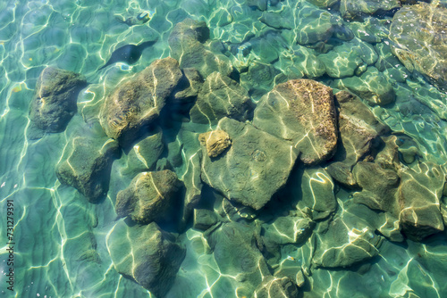 Rocks under gleaming transparent aquamarine sea water   © Olga