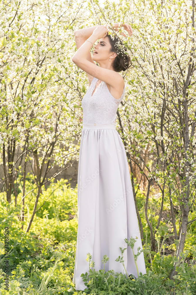 Beautiful brunette in a wedding dress in blooming trees. Beautiful brunette in a wedding dress in blooming trees.