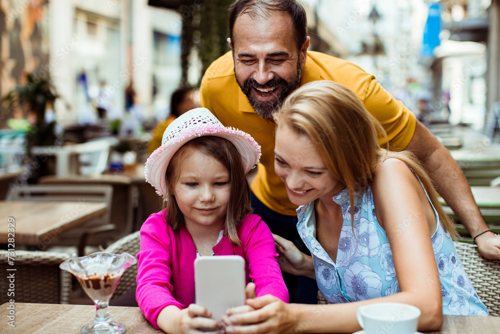 Family Enjoying Time Together at a Cafe with Smartphone Family Enjoying Time Together at a Cafe with Smartphone