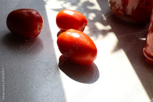 Ripe tomatoes on the kitchen table, shadows from objects