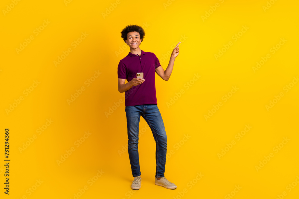 Full length photo of nice satisfied man wear trendy polo reommend buy modern technology empty space isolated on yellow color background Full length photo of nice satisfied man wear trendy polo reommend buy modern technology empty space isolated on yellow color background