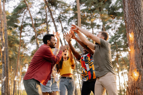 Foto Multiracial group of people, friends give high five and having fun on the picnic