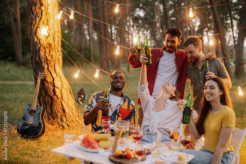 Group of multiracial friends having fun at party, drinking beer and making toast