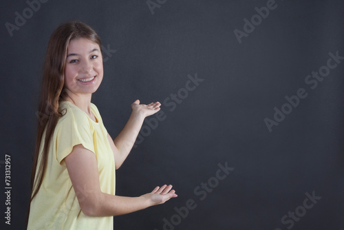 Portrait of a beautiful young woman pointing with her hand at copy space photo