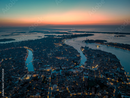 Aerial picture of Venice with famous illuminated landmarks and sunrise colours in the sky during morning blue hour