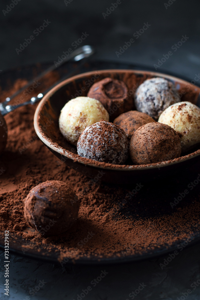 Truffle candies in cocoa on a plate on a dark background. Assorted chocolate truffles. Close. Truffle candies in cocoa on a plate on a dark background. Assorted chocolate truffles. Close.