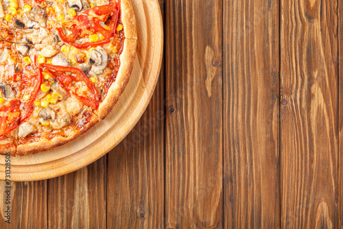 delicious pizza with chicken, mushrooms, cheese, tomatoes and corn on a wooden background