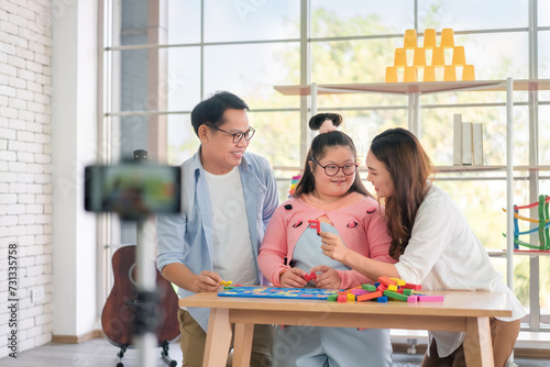 Happy asian father and mother playing education toy with their daughter down syndrome child, As vlogger and live stream online, Activity happy family lifestyle concept.