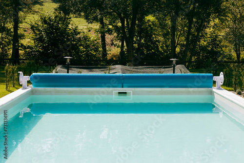 Swimming pool cover for protection against dirt, leaves, heating and cooling water, copy space. Blue tarpaulin pool cover. Summer day