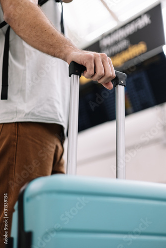 closeup man in airport holding suitcase handle