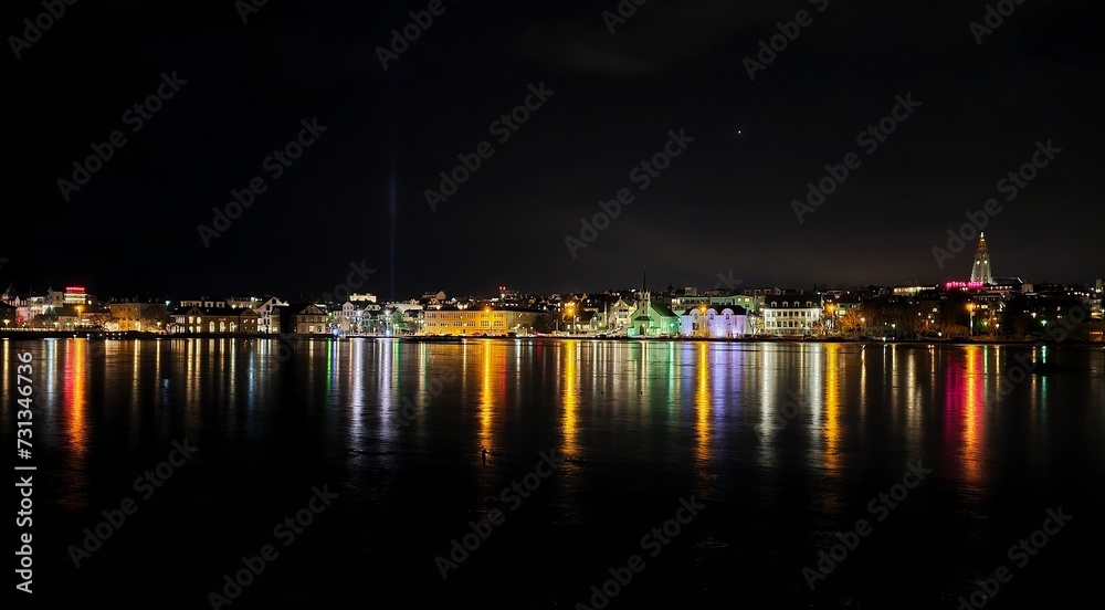 colorful lights reflecting off of the water at night in an urban city
