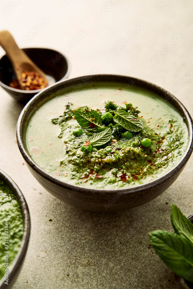 Pea mint and kale soup on light green background with chilli Pea mint and kale soup on light green background with chilli
