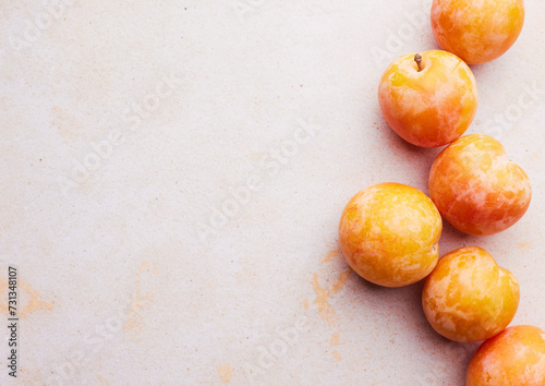 Yellow plums on a light pink background photo