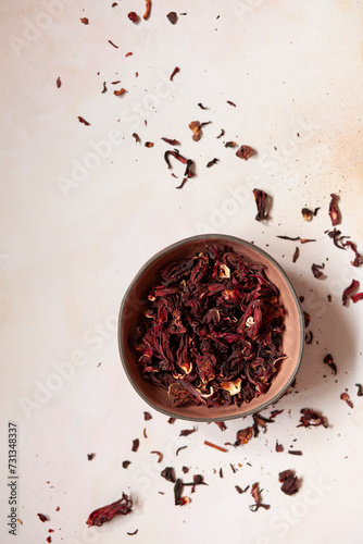 Dried hibiscus flowersin a bowl on a pink worktop.