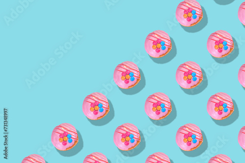 Modern retro color theme pattern of pink donuts against an aqua blue background with negative copy space. photo
