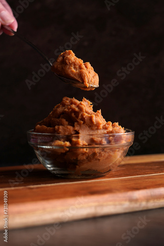 Healthy probiotic Japanese style miso against a dark background. Female hand with spoonful.