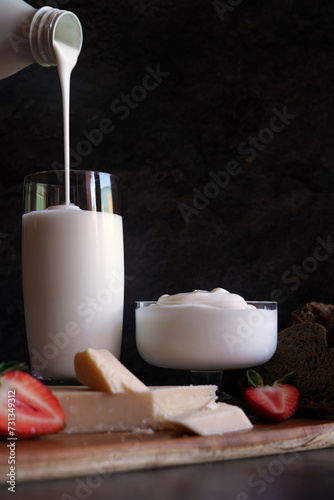 Healthy probiotic dairy, including kefir, Greek style yoghurt, and parmgiano reggiano. Pouring kefir from bottle. photo