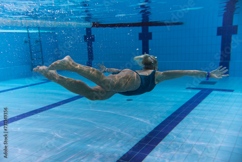 Underwater photo, girl swimming in a sports pool, side view.