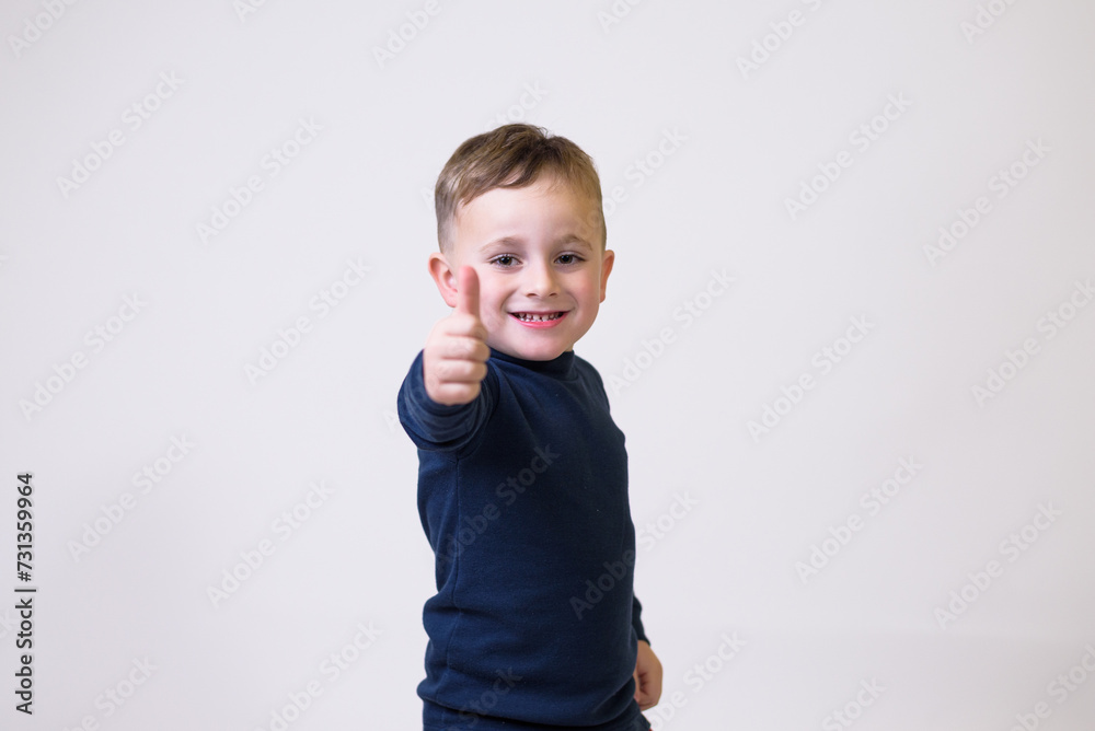 Portrait of cute boy in casual clothes showing thumbs up sign on white background Portrait of cute boy in casual clothes showing thumbs up sign on white background