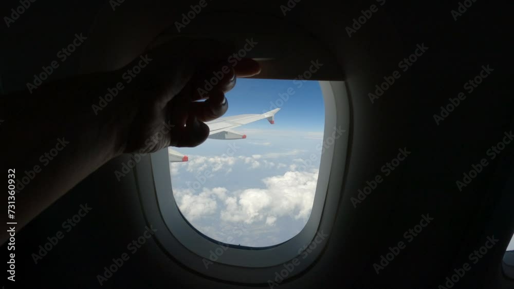 POV: Air passenger closes the curtain on the plane window during the flight. A traveller lowers the blind to rest during long airplane ride to faraway places. Comfortable travel by air transportation.