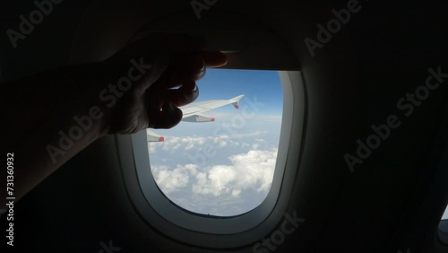 POV: Air passenger closes the curtain on the plane window during the flight. A traveller lowers the blind to rest during long airplane ride to faraway places. Comfortable travel by air transportation. photo