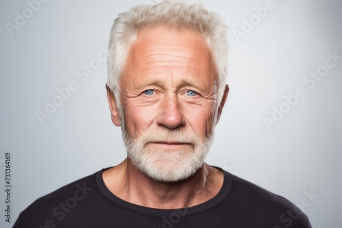 Portrait of a senior man with grey hair and beard on grey background © Inigo