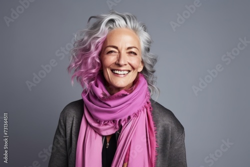 Portrait of a happy senior woman with pink scarf over grey background