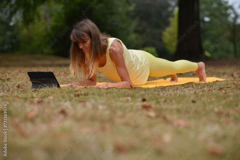 Fototapeta premium A middle-aged woman is doing yoga in the park
