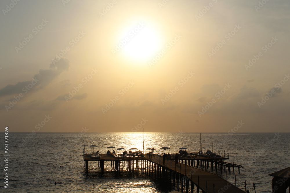 Obraz premium sunset on the beach. sea ​​pier on the background of a beautiful sunset over the sea 