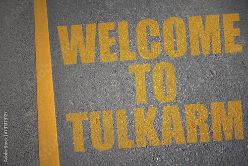 asphalt road with text welcome to Tulkarm near yellow line. photo