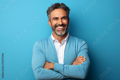 Portrait of happy mature man with arms crossed over blue background.